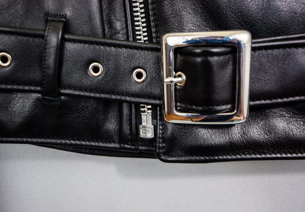 Close-up of a black leather belt with a silver buckle on a gray background