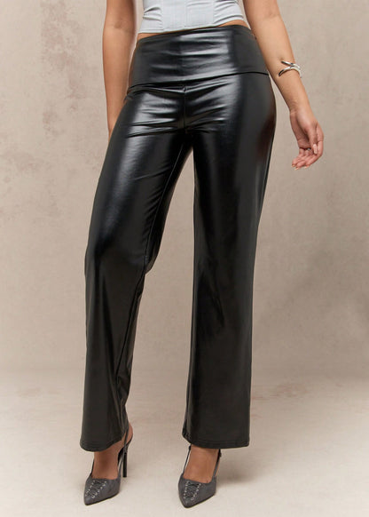 Person wearing black leather pants on a neutral background