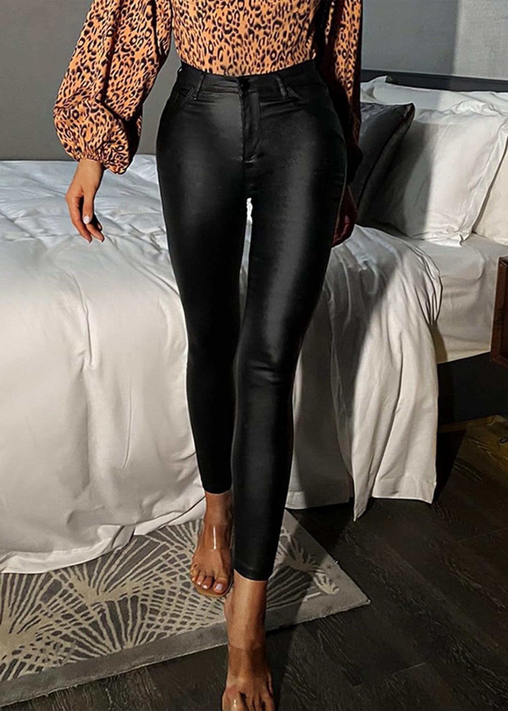 Person wearing a leopard print top and black pants in a bedroom setting