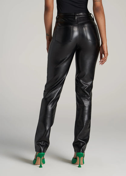 Person wearing black leather pants on a plain background